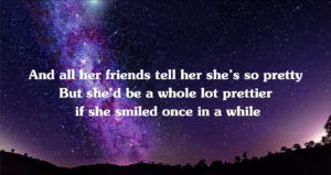 Screenshot from a YouTube "lyrics" video of a Shawn Mullins song titled "Lullaby".

The background is a night Milky Way photo.

The lyrics at this point read...
"And all her friends tel her she's so pretty. But she'd be a whole lot prettier if she smiled once in a while."